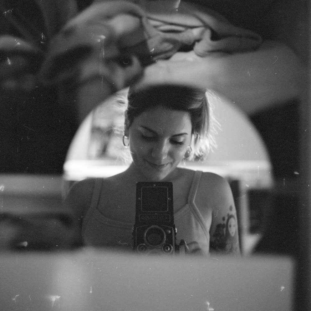 Self-portrait in an arched mirror with a twin-lens film camera