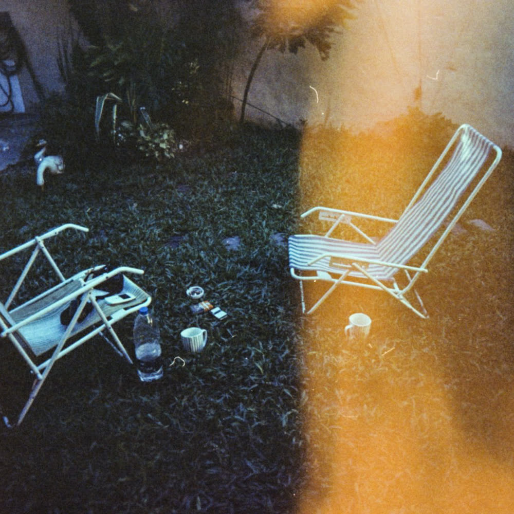 Two folding chairs in a garden at night, cut by a light leak