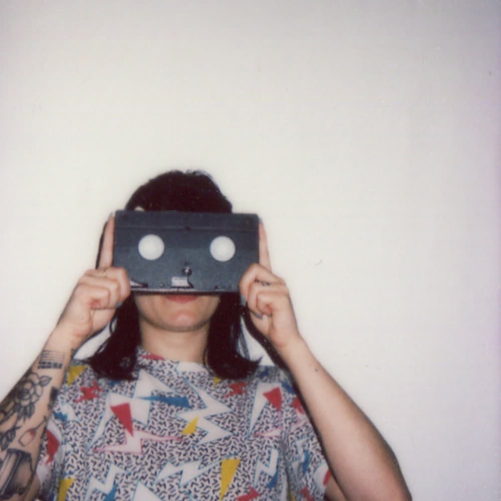 A Polaroid of someone holding a VHS tape over their eyes